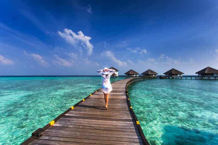 Mulher andando em ponte sobre a água nas Maldivas