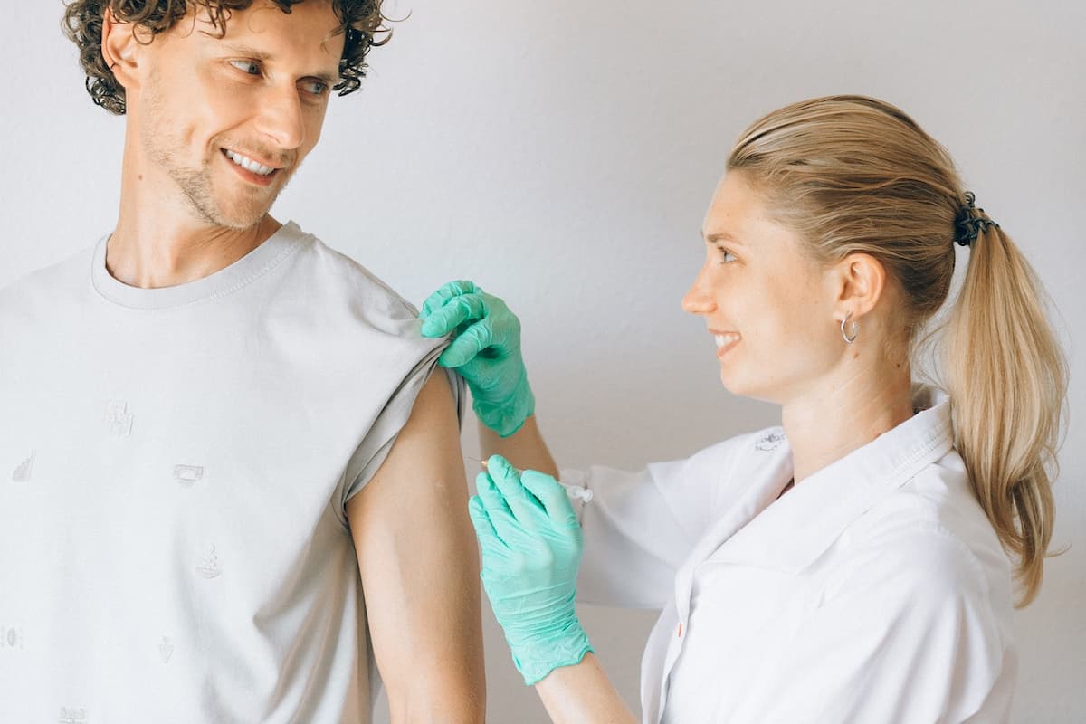 Homem sendo vacinado por mulher