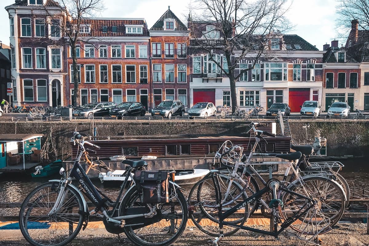 Imagem de bicicletas na frente de casas históricas com um barco ao fundo