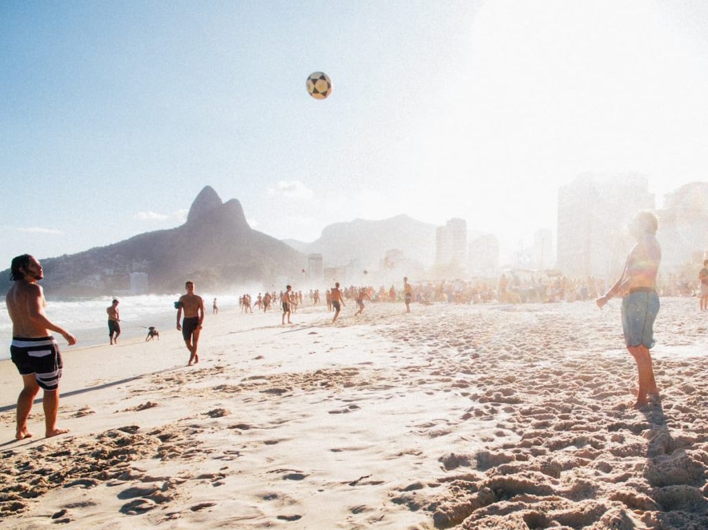 Pessoas jogando futebol de praia na frente do mar de Ipanema