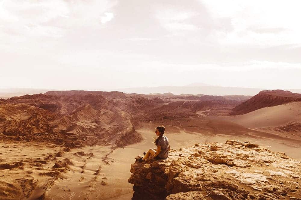 Mulher sentada no topo de uma montanha no deserto
