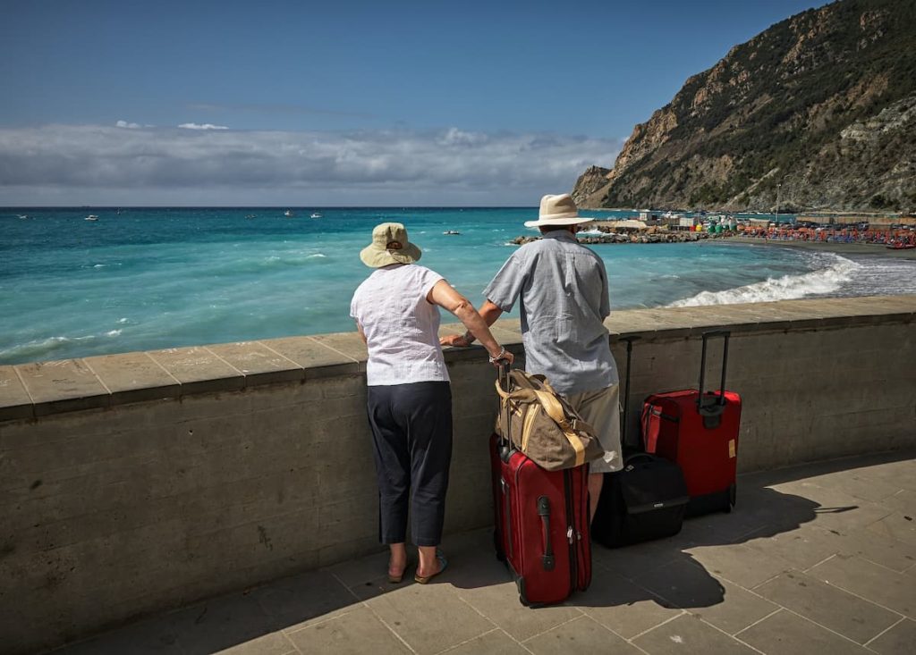 Homem e mulher com malas apreciando a paisagem de uma praia