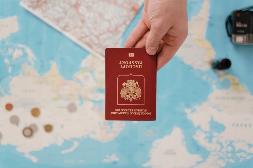 Pessoa segurando um passaporte na frente de um mapa de papel