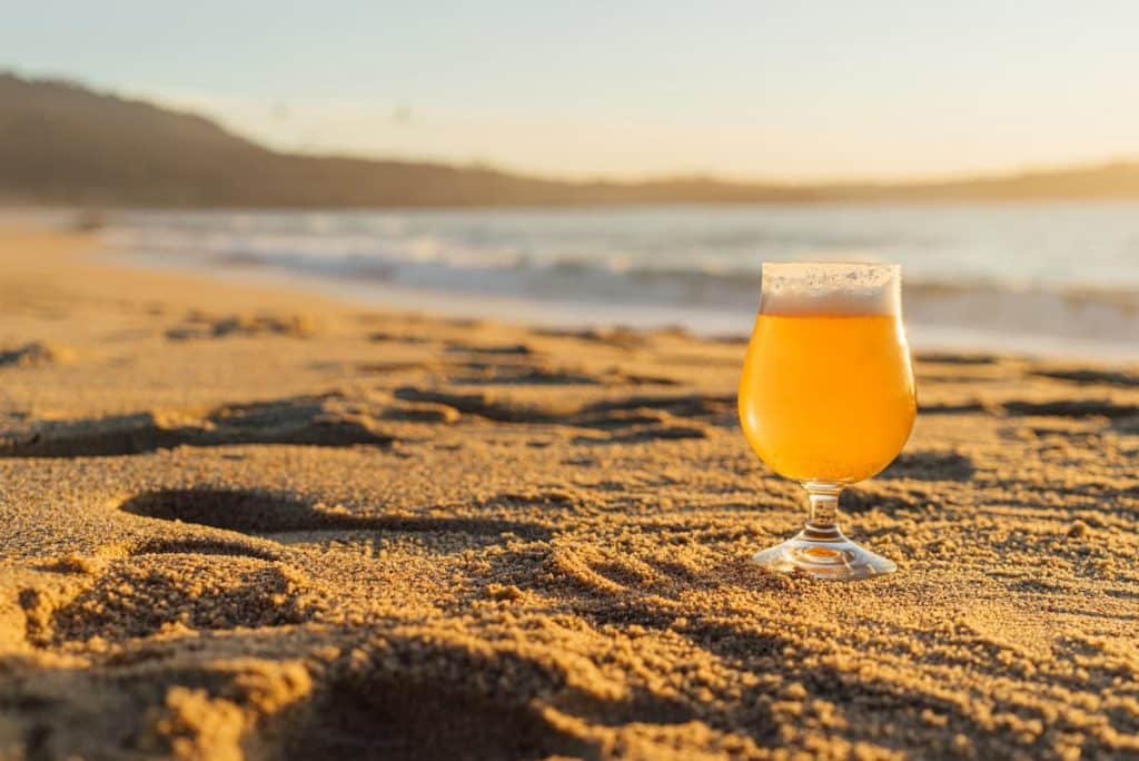 Copo de cerveja na areia de uma praia