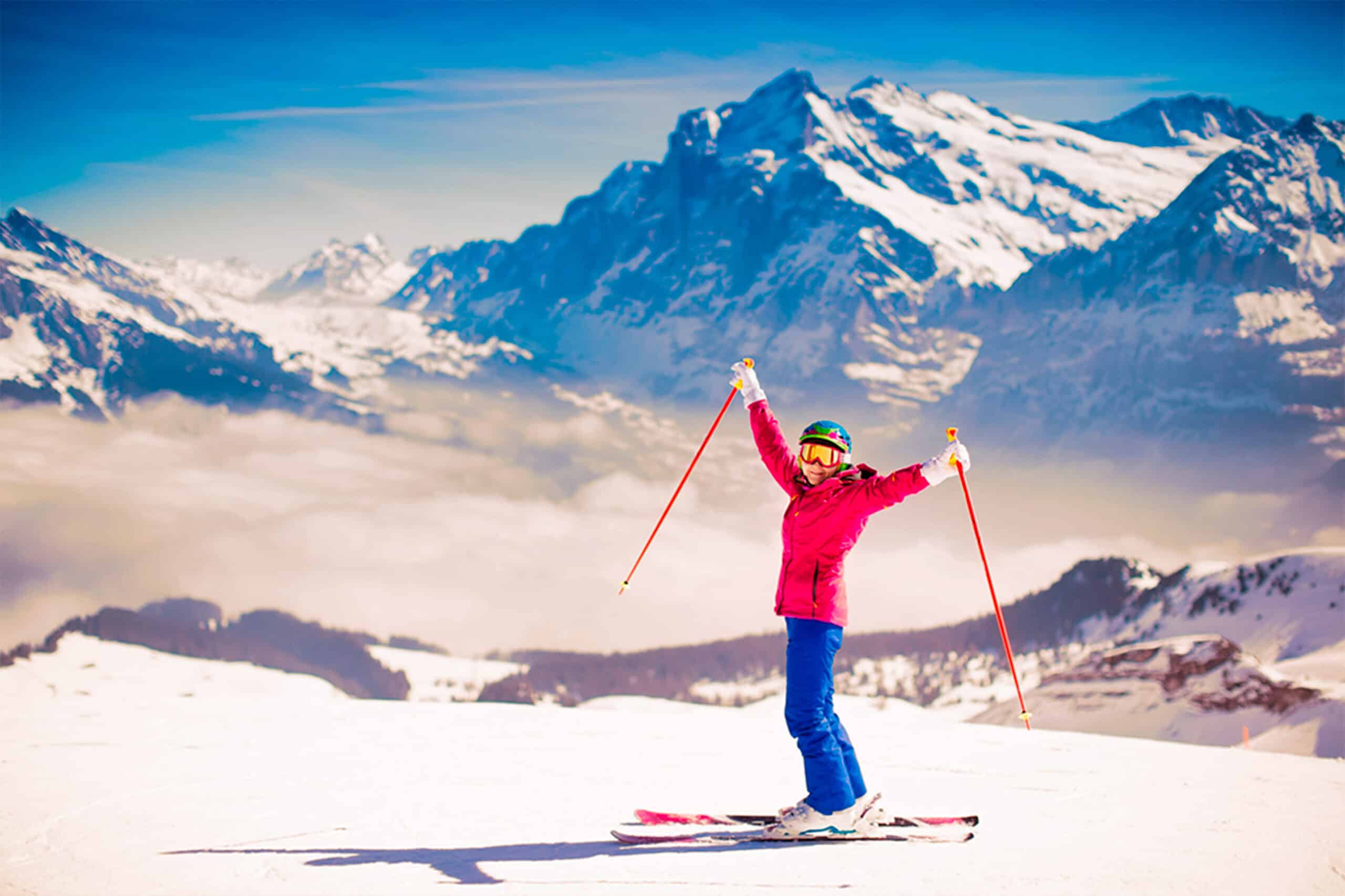 Pessoa na neve com roupa de esquiar colorida com os braços para cima
