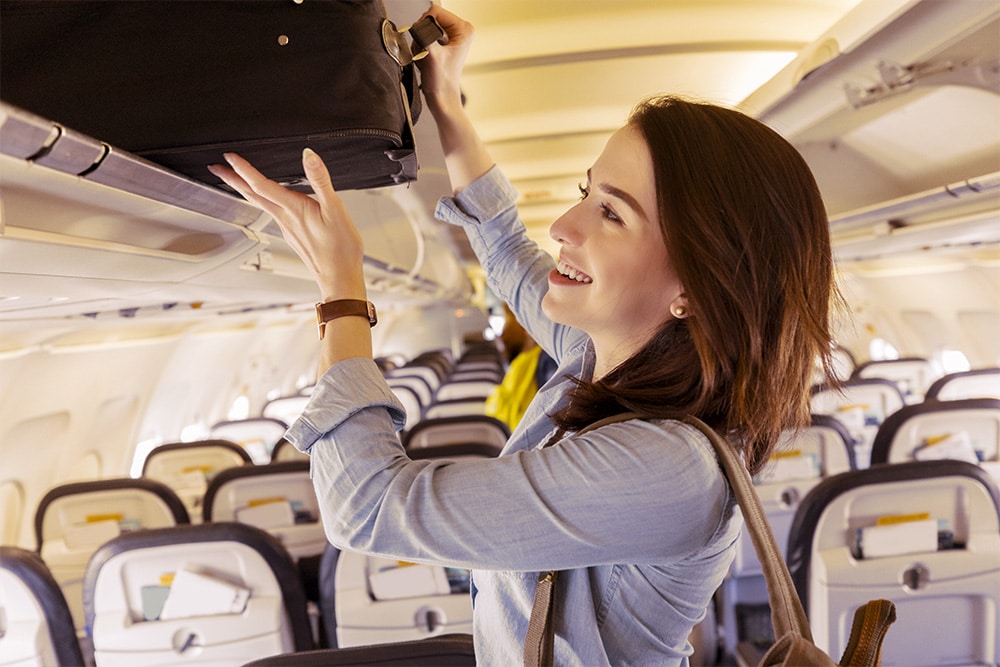 pessoa colocando mala em um compartimento no interior de um aviação