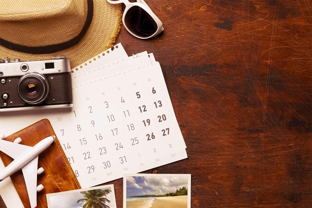 mesa com objetos em cima; chapéu, calendário, fotos, óculos