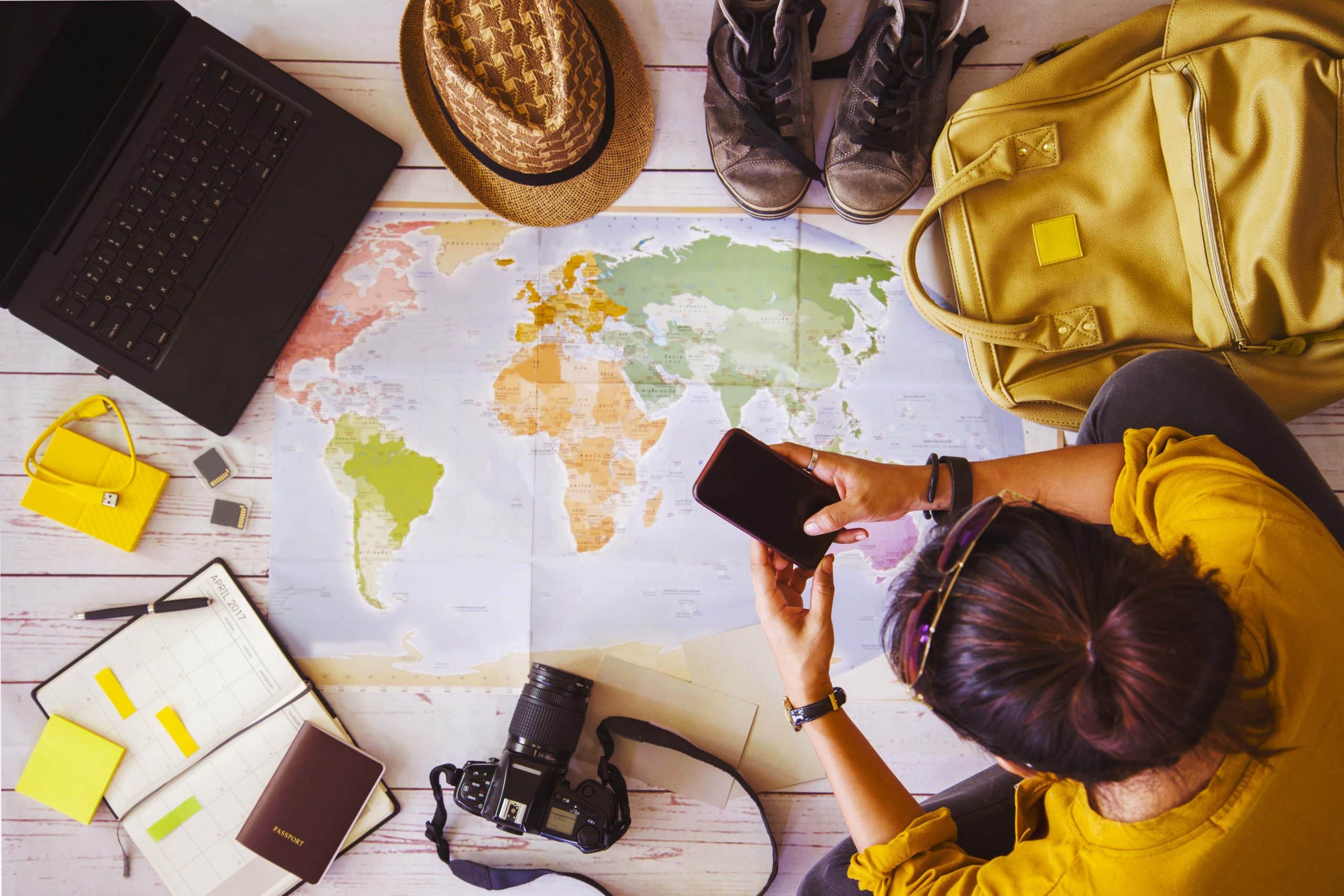 pessoa planejando viagem com um mapa, mochila, passaporte e notebook