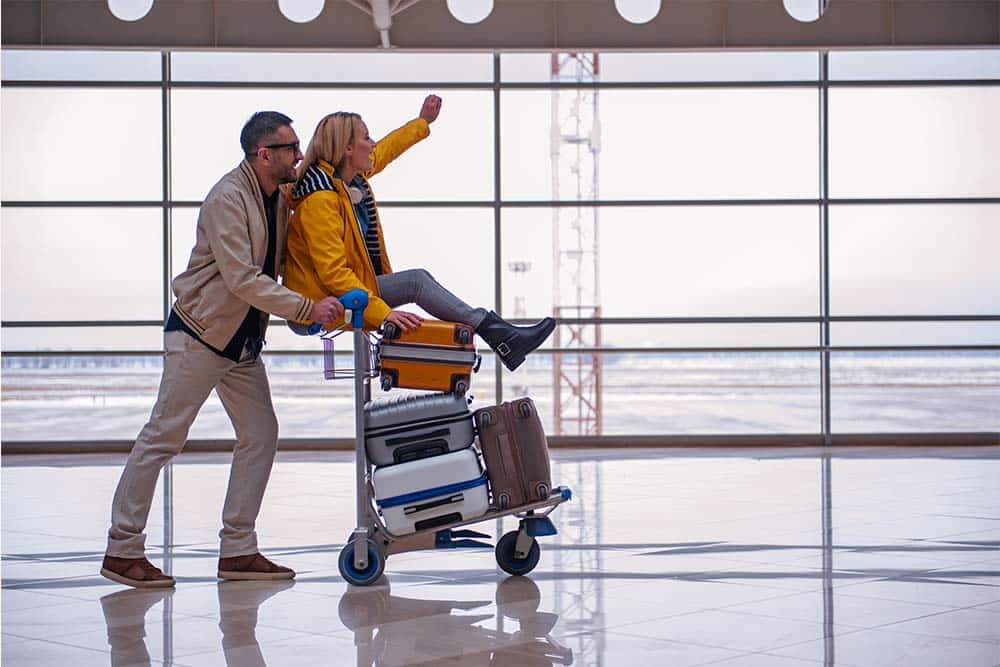 Homem e mulher no aeroporto com carrinho de bagagens