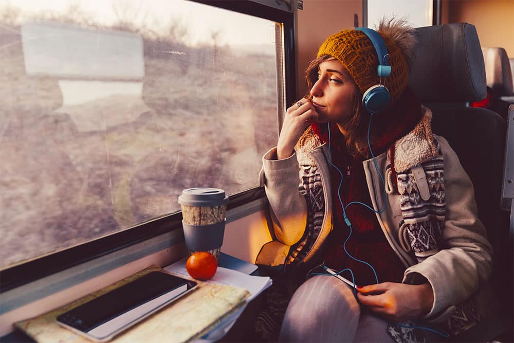 mulher com fones de ouvido olhando a janela em um trem