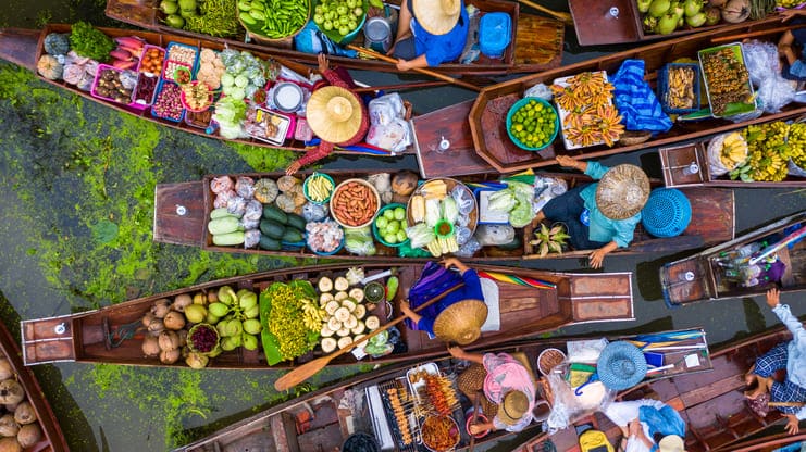 Tailândeses transportando alimentos de barco a remo