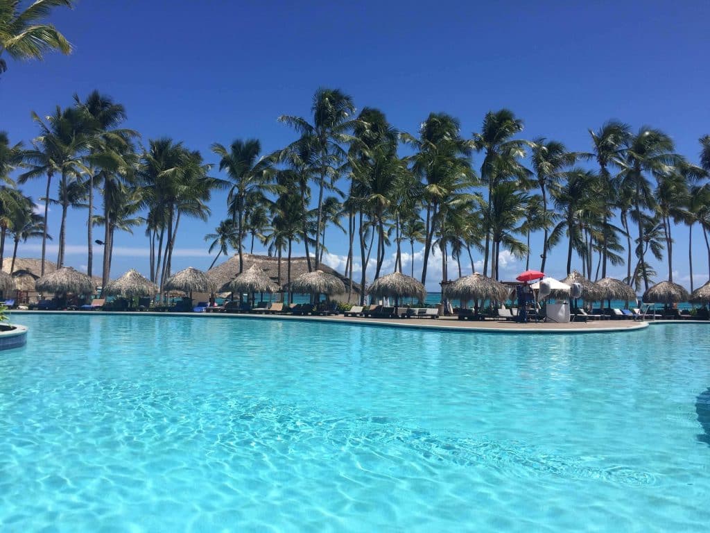 Resort em Punta Cana com piscina, palmeiras e guarda-sol.