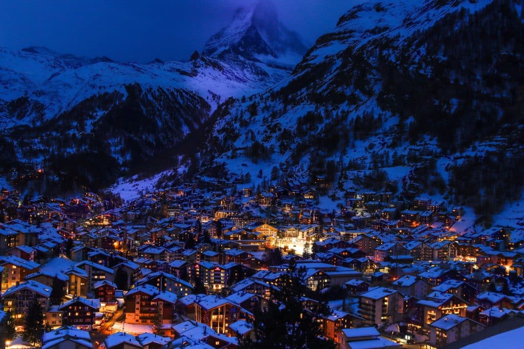 Cidade da Suíça com montanhas cobertas de neve ao redor.