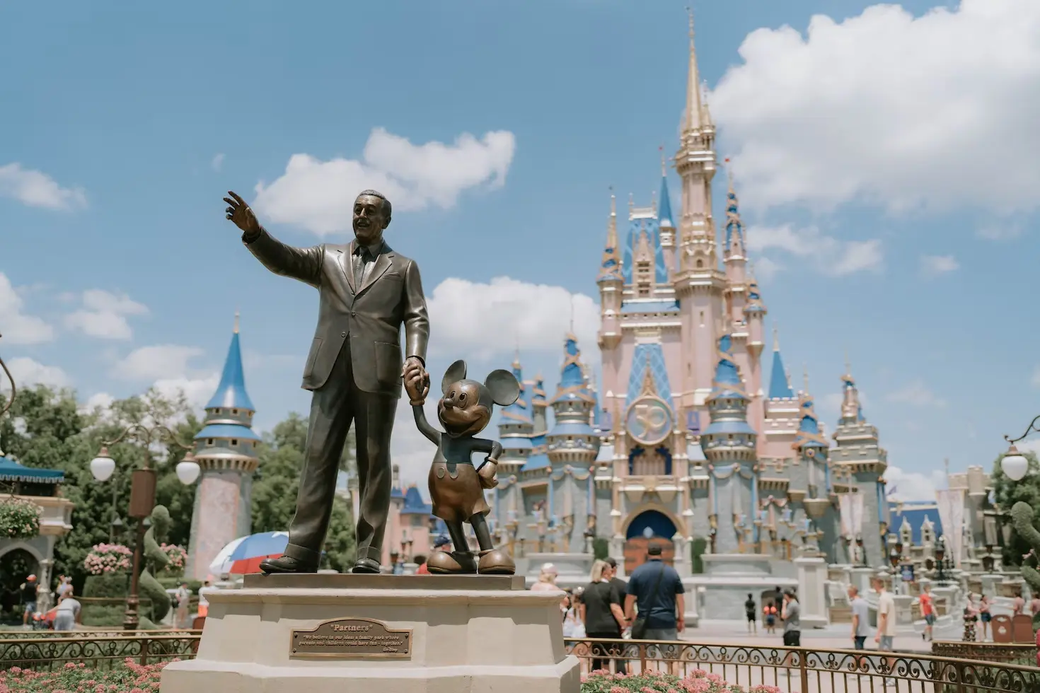 Estátua do Walt Disney de mãos dadas com o Mickey em frente ao castelo da Disney