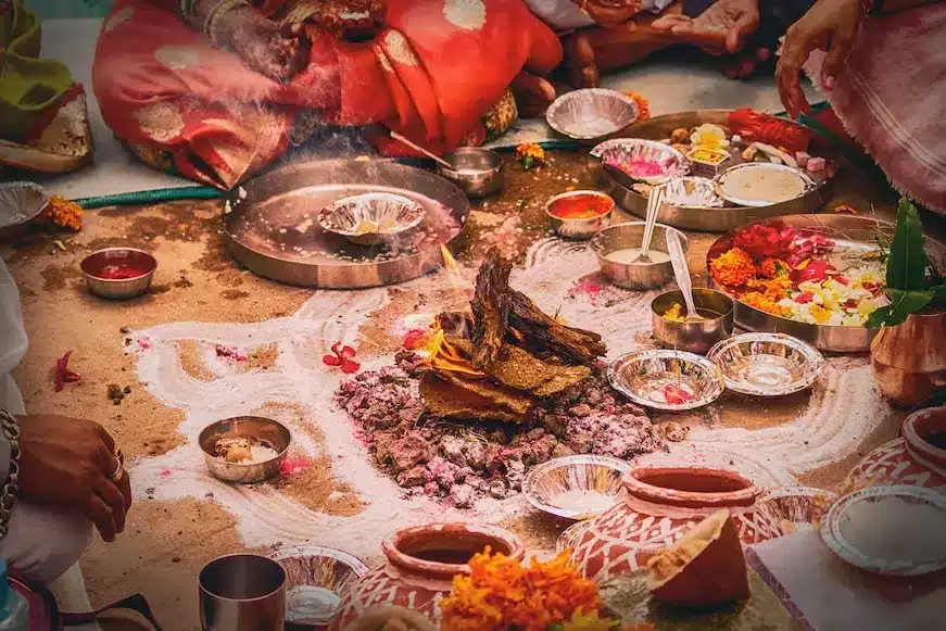 Braços, pernas e mãos de pessoas com roupas tópicas indianas sentado ao chão em volta de vários pratos típicos indianos