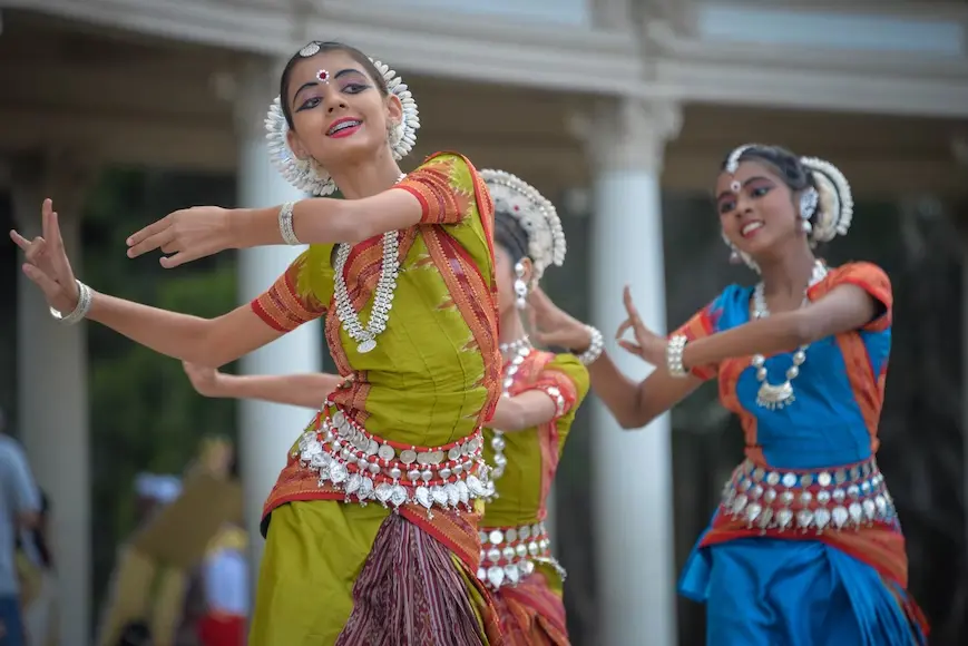 Três meninas com roupas e acessórios típicos indianos dançando