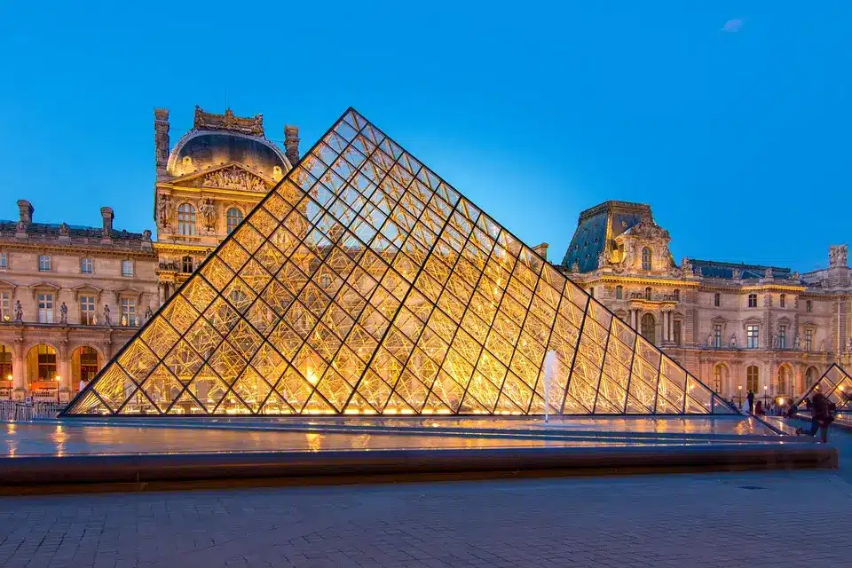 Foto da pirâmide do museu do Louvre, em Paris, com o museu atrás