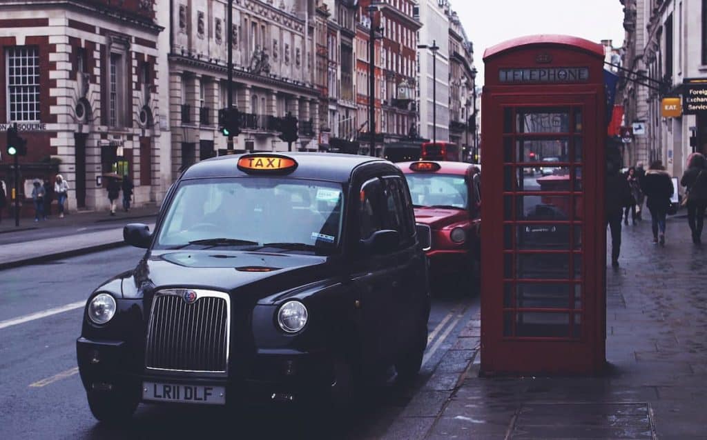 Táxi preto ao lado da cabine telefônica vermelha 