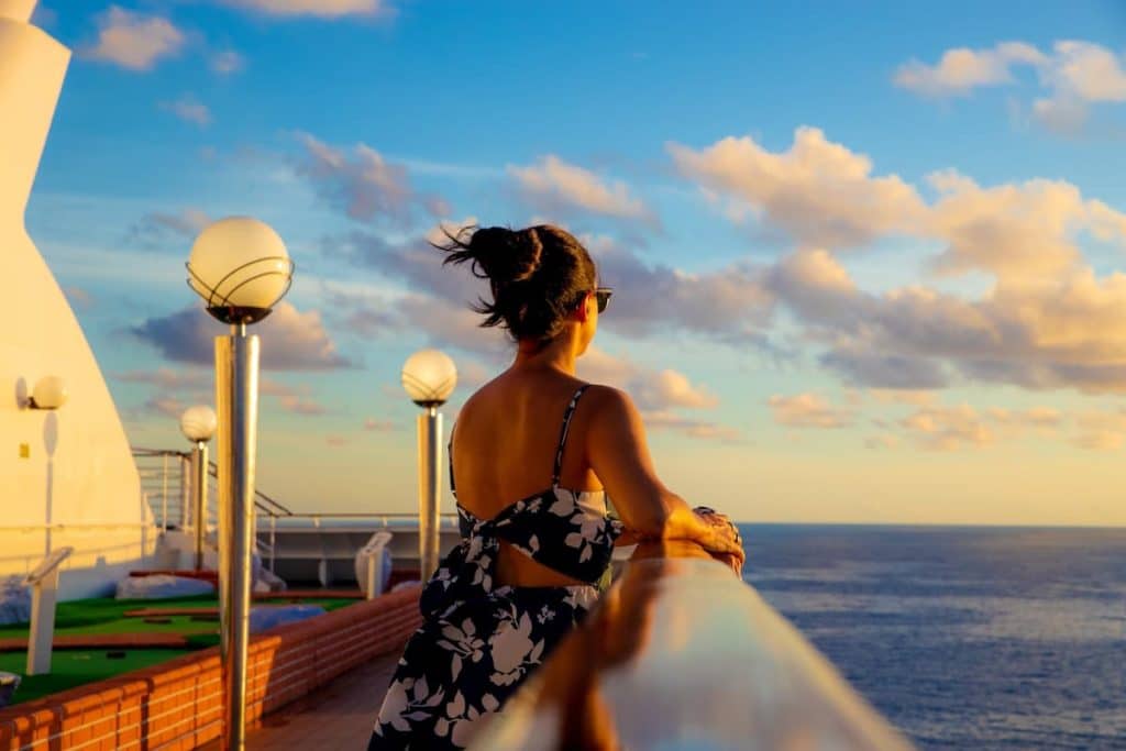 Imagem de uma mulher de pé olhando para o oceano de um navio