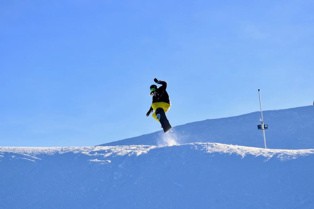 Homem voando enquanto pratica snowboard na neve