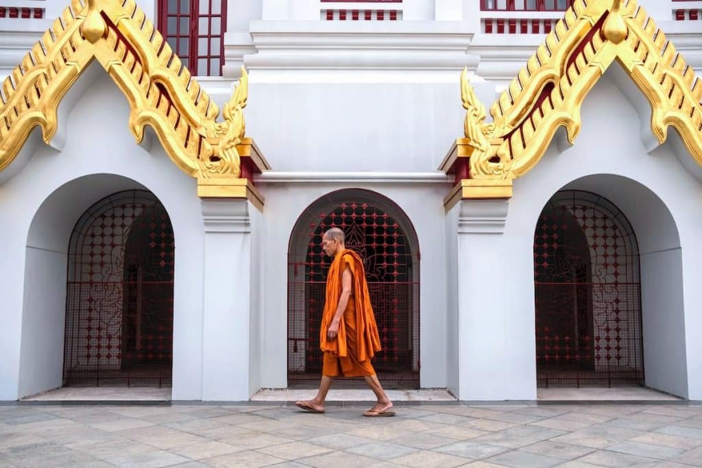 Monge andando na frente de um templo budista